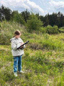Bērns ar interesi plāno nākotnes aktivitātes angļu valodas nometņu dabas vietā